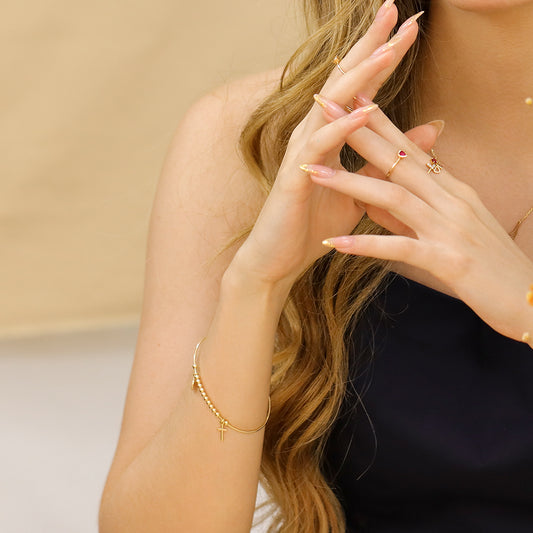 Brazo de mujer usado una pulsera brazalete denario en oro amarillo de 18 quilates. 