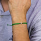 Mano de hombre con pulsera tejida en hilo verde, accesorios en color verde, amarillo y dije de estrella en oro amarillo de 18 quilates, hecho en Joyería Caracas. 