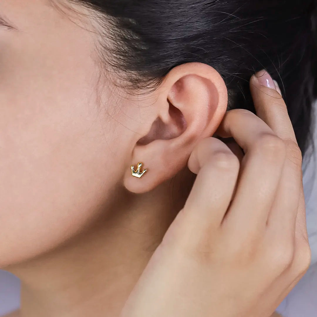 Oreja de mujer con topitos en forma de corona en oro amarillo de 18 quilates, hechos en Joyería Caracas. 