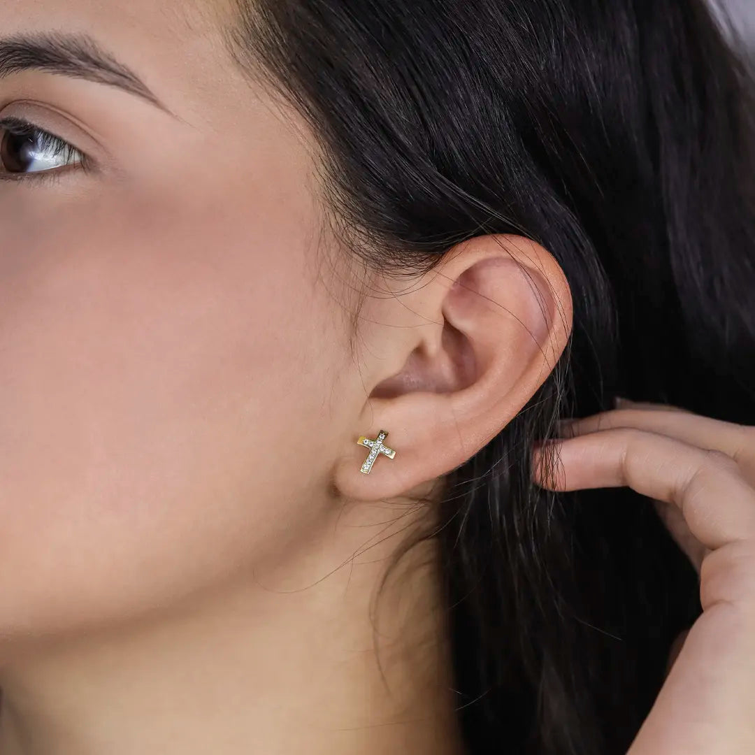 Oreja de mujer con topito en forma de cruz en oro amarillo de 18 quilates con cristales de color blanco, hechos en Joyería Caracas. 