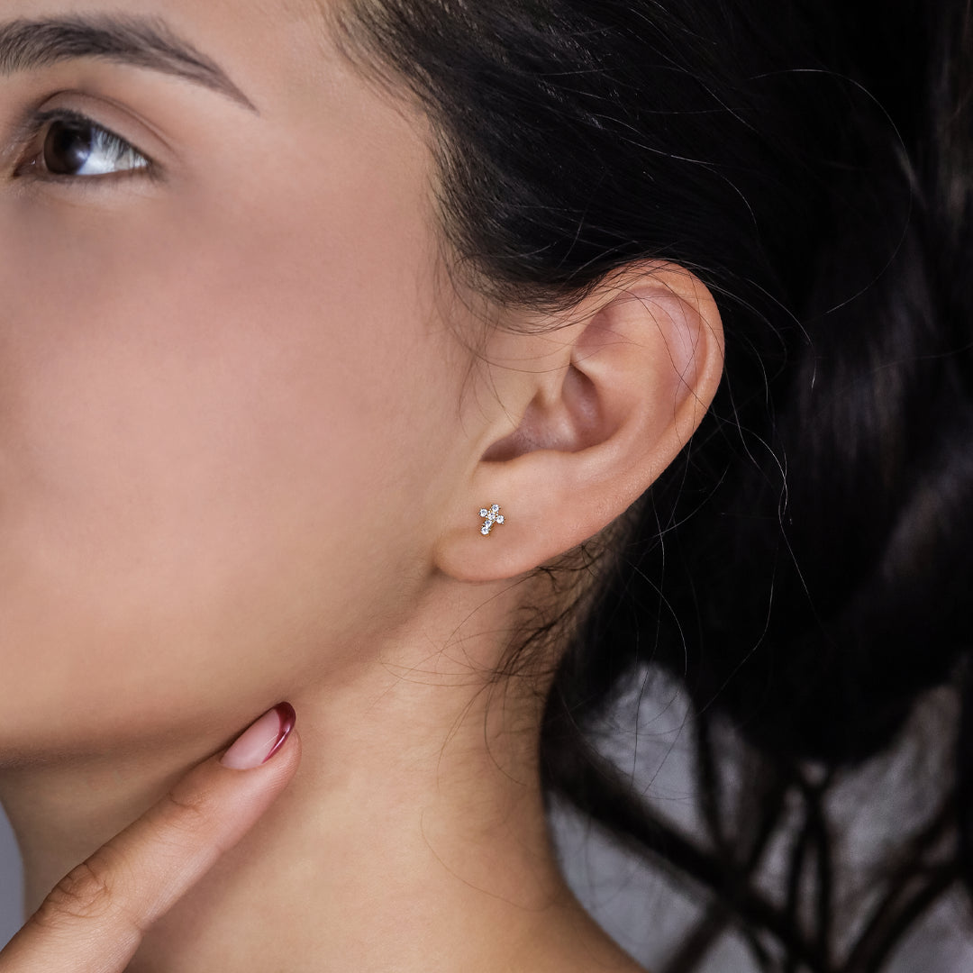 Oreja de mujer con topito en forma de cruz en oro amarillo de 18 quilates con cristales de color blanco, hechos en Joyería Caracas. 