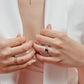 Mano de mujer con anillo en oro amarillo de 18 quilates, con cristales de color blanco y cristal de color azul en forma cuadrada, hecho en Joyería Caracas. 