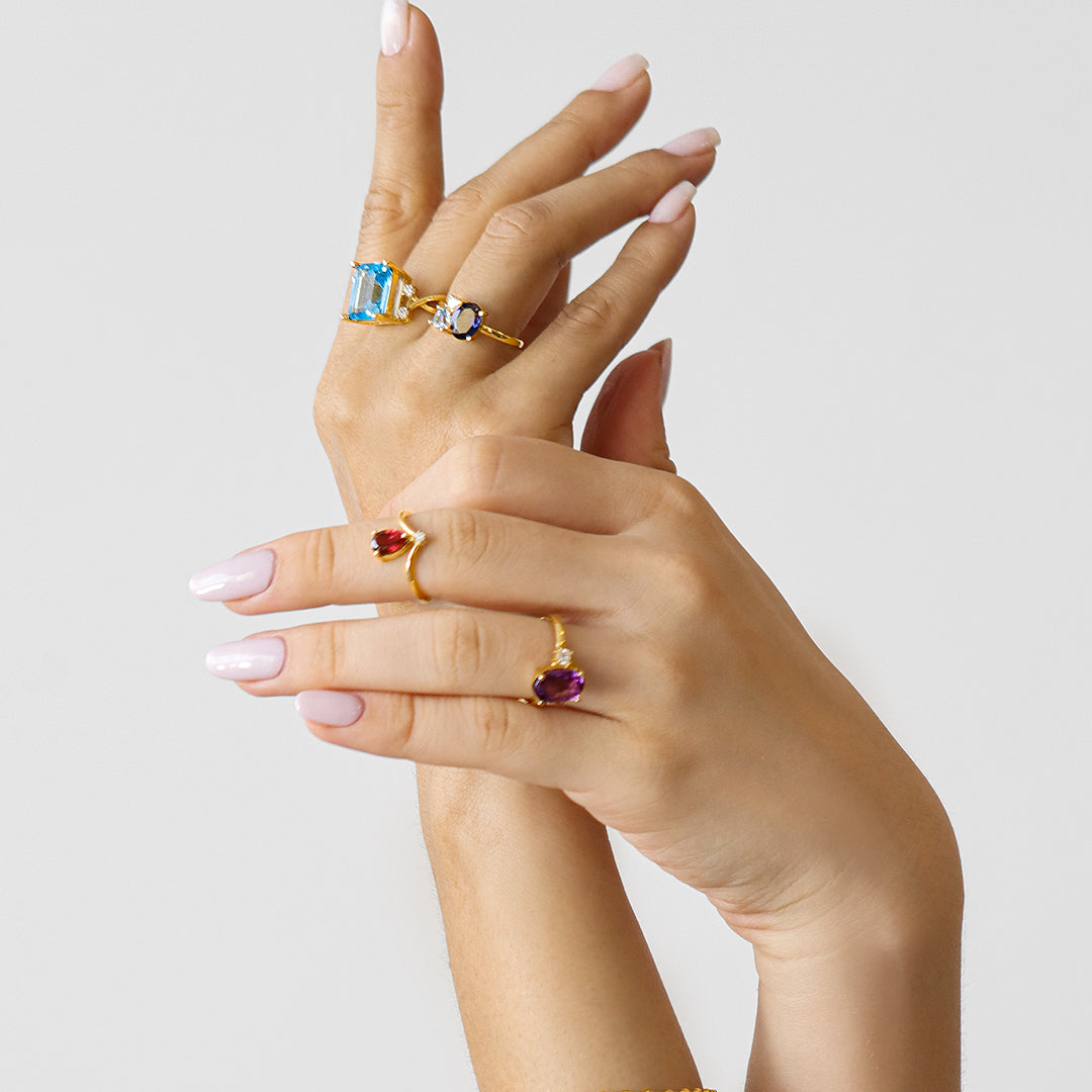 Mano de mujer con anillo en oro amarillo de 18 quilates con Topacio en el centro y 4 diamantes de color blanco, hecho en Joyería Caracas. 