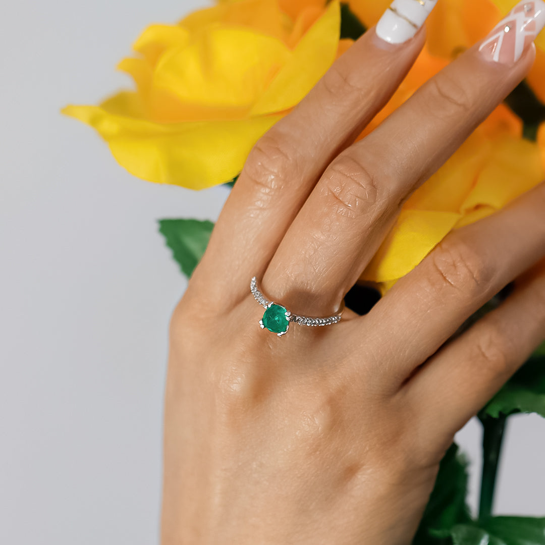 Mano de mujer con anillo en oro blanco de 18 quilates con esmeralda, cuenta con garantía de por vida. 