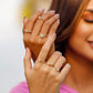 Mano de mujer con anillo y pisargolla en oro amarillo de 18 quilates con cristales de color blanco, hecho en Joyería Caracas. 