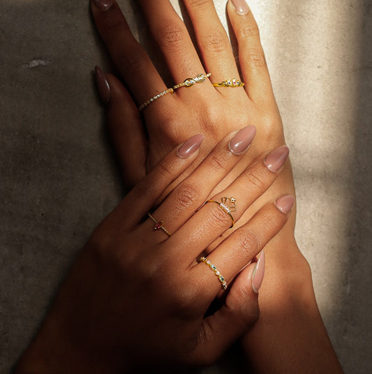 Mano de mujer usando anillo con corona en el centro en oro amarillo de 18 quilates y cristales de color blanco, hecho en Joyería Caracas. 
