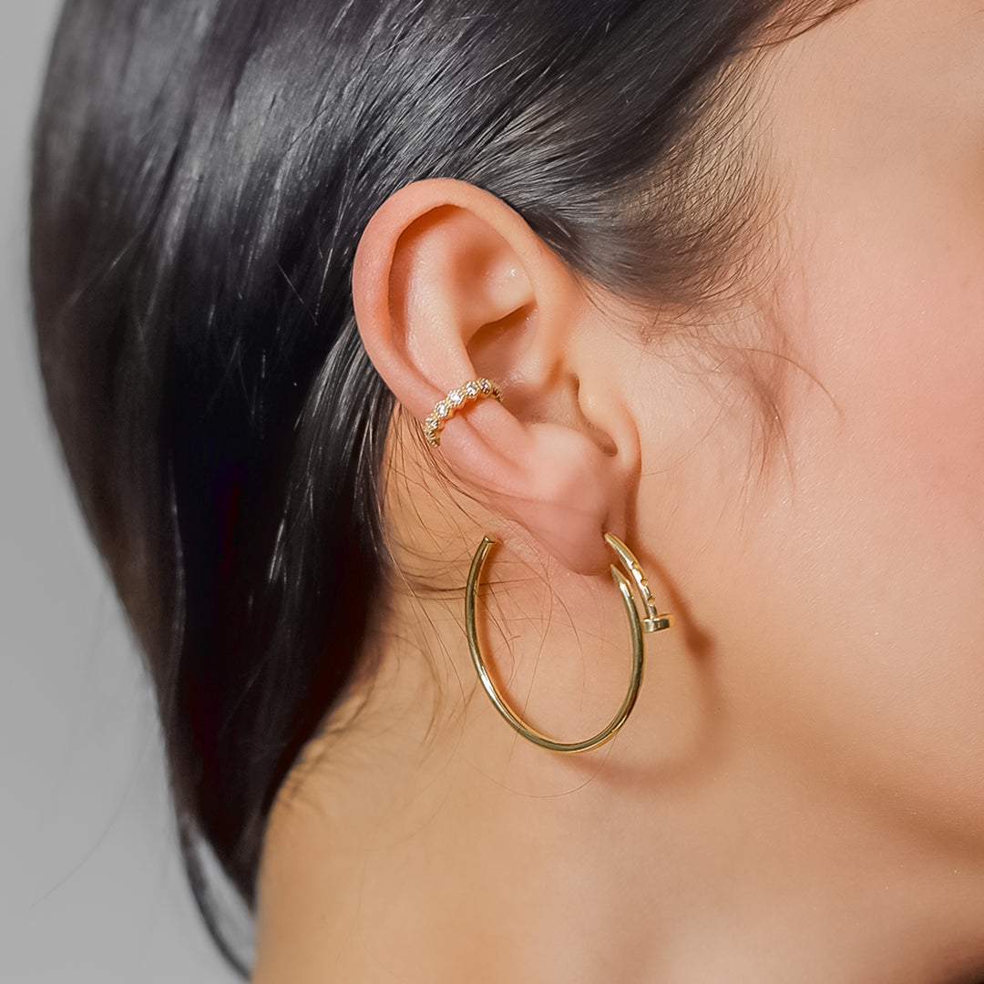 Oreja de mujer con earcuff en oro amarillo de 18 quilates y cristales de color blanco, hecho en Joyería Caracas. 