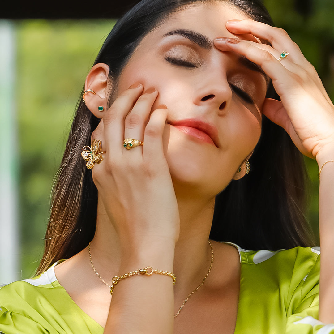 Mano de mujer con anillo en forma de Búho en oro amarillo de 18 quilates con 2 cristales de color verde, hecho en Joyería Caracas.  