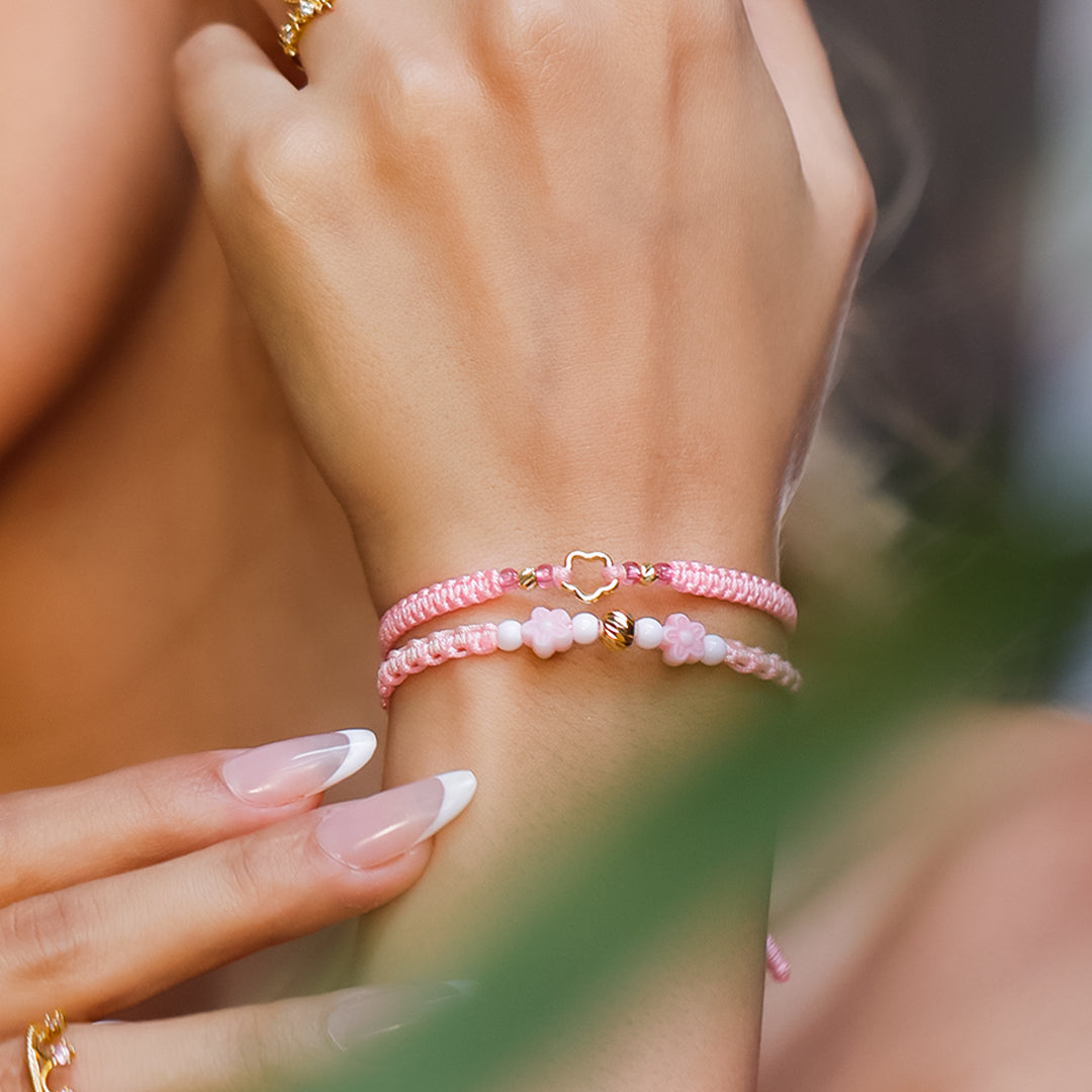 Mano de mujer con pulsera tejida en hilo rosa, bisutería y esfera facetada en oro amarillo de 18 quilates, hecho en Joyería Caracas. 