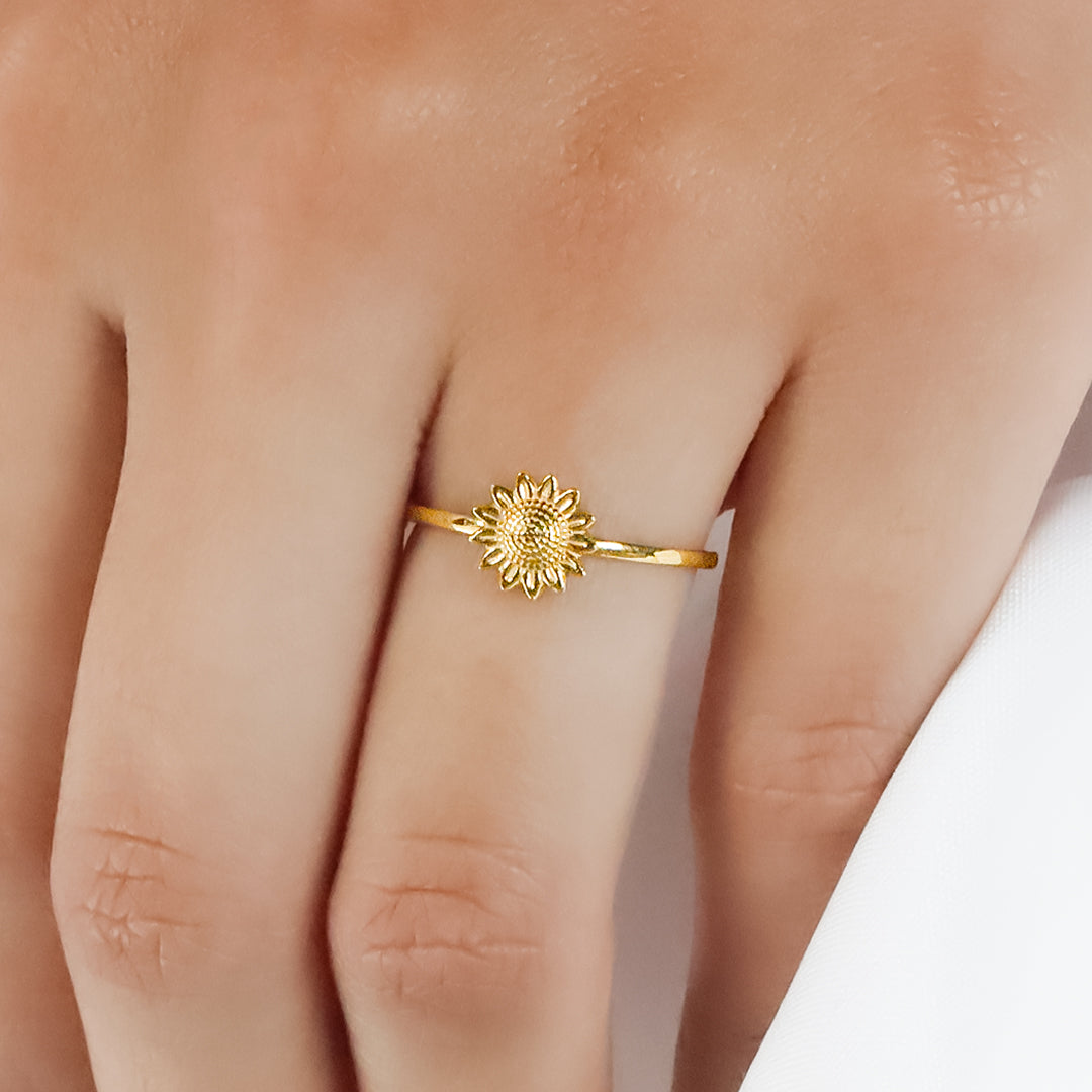 Mano de mujer usando anillo con forma de girasol en el centro en oro amarillo de 18 quilates, hecho en Joyería Caracas. 