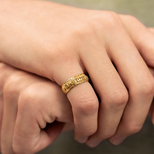 Mano de hombre con anillo de grado en oro de 18k amarillo con cristales de color blanco, hecho en Joyería Caracas. 