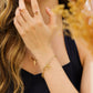 Modelo usando una pulsera de eslabones grandes con un corazón y cruz en oro amarillo de 18 quilates de Joyería Caracas.
