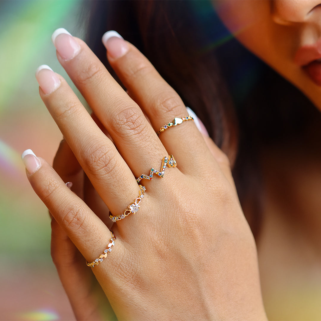 Mano de mujer usando anillo con formas de corazones alrededor en oro amarillo de 18 quilates, con diamantes de color blanco y piedra topacio en el centro, hecho en Joyería Caracas. 