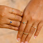Mano de mujer con anillo en oro amarillo de 18 quilates con cristal en forma de corazón de color azul, hecho en Joyería Caracas. 