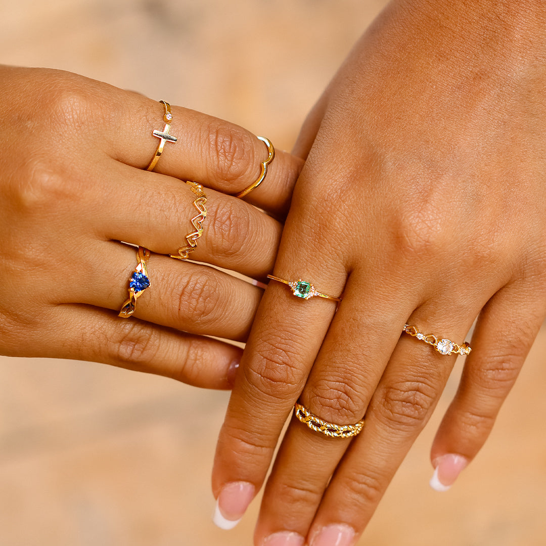 Mano de mujer con anillo en oro amarillo de 18 quilates con cristal en forma de corazón de color azul, hecho en Joyería Caracas. 