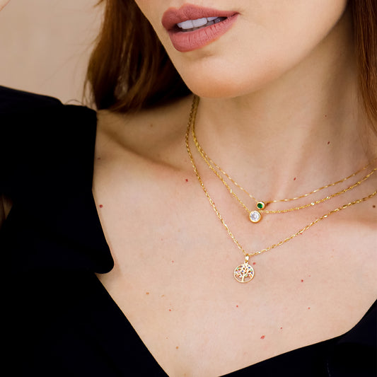 Cuello de mujer con gargantilla y dije pasante en oro amarillo de 18 quilates y cristal de color verde, hecho en Joyería Caracas. 