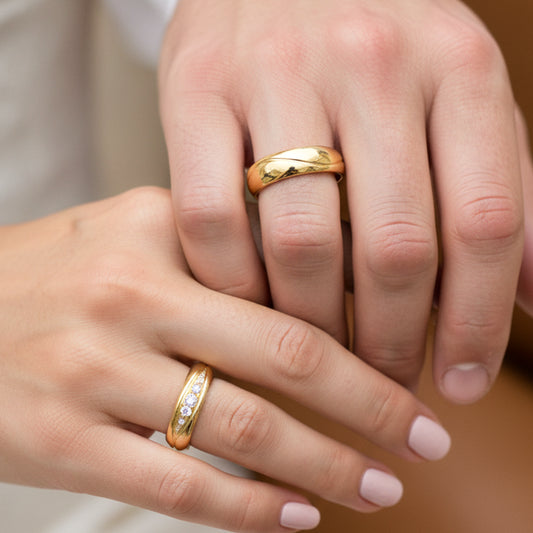 Mano de pareja en matrimonio usando unas argollas de matrimonio en oro amarillo de 18 quilates con cristales de Joyería Caracas. 