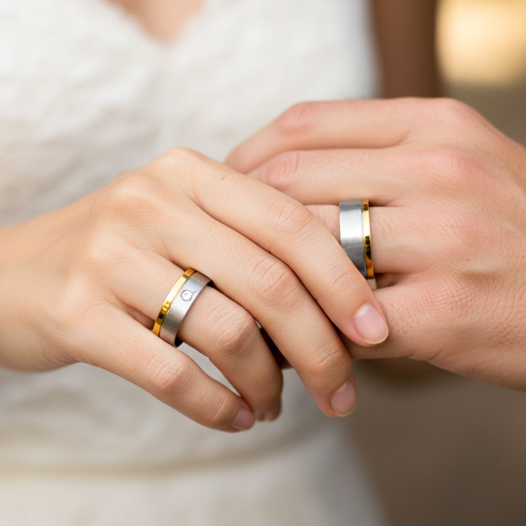 Mano de pareja en matrimonio usando unas argollas de matrimonio en oro blanco y amarillo de 18 quilates con cristal de Joyería Caracas. 