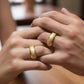 Mano de pareja usando unas argollas de matrimonio facetadas en oro amarillo de 18 quilates de Joyería Caracas.