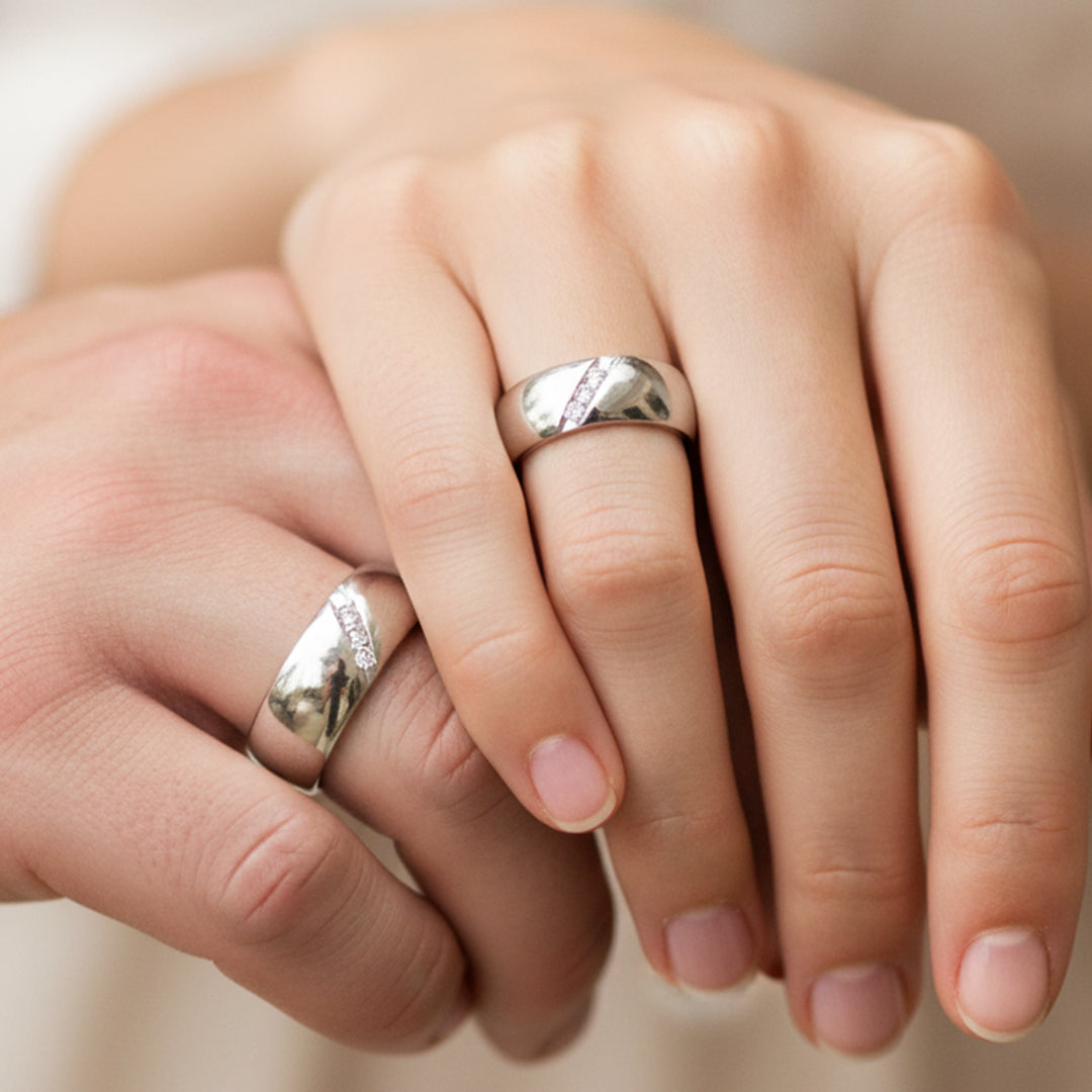Mano de pareja usando unas argollas de matrimonio en oro blanco de 18 quilates con cristales de Joyería Caracas. 