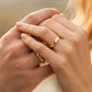 Mano de pareja usando unas argollas de matrimonio en oro amarillo de 18 quilates de Joyería Caracas. 