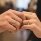 Mano de pareja usando unas argollas de matrimonio en oro amarillo de 18 quilates de Joyería Caracas. 