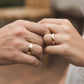 Mano de pareja usando unas argollas de matrimonio en oro amarillo de 18 quilates de Joyería Caracas. 
