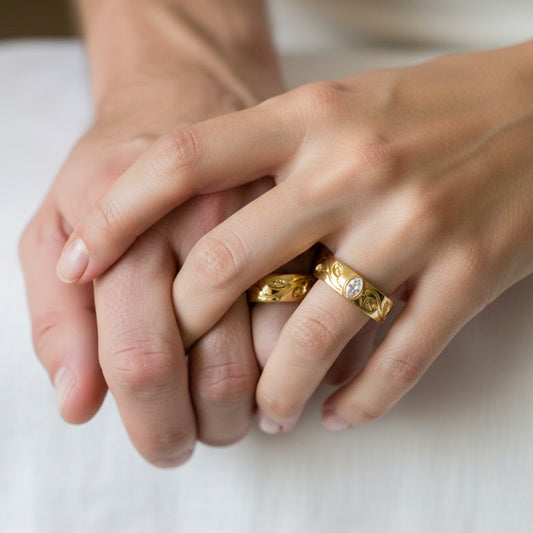 Mano de pareja en matrimonio usando unas argollas de matrimonio con diseño de ramas en oro amarillo de 18 quilates con cristal de Joyería Caracas. 