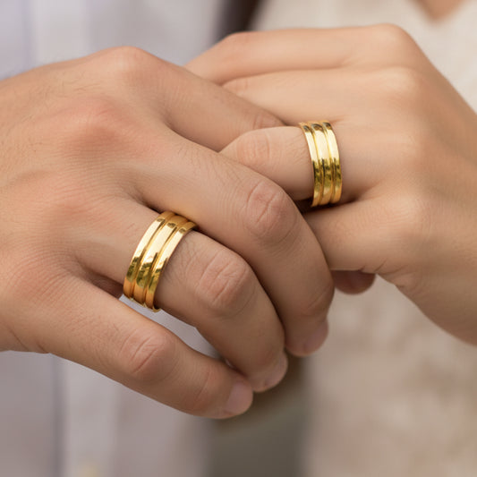 Mano de pareja usando unas argollas de matrimonio 3 canales en oro amarillo de 18 quilates de Joyería Caracas. 