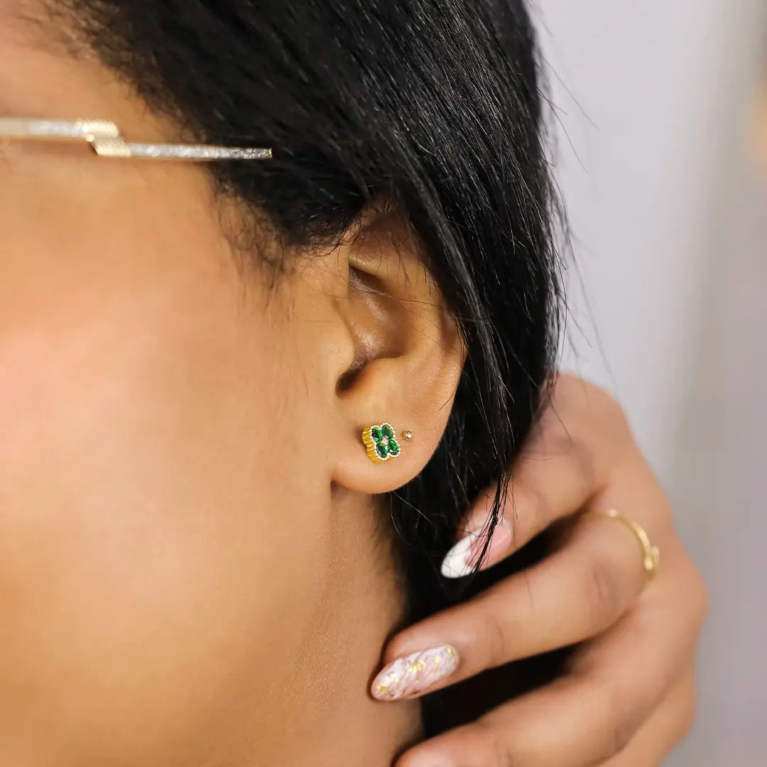 Oreja de mujer con topito en forma de trébol en oro amarillo de 18 quilates con 4 cristales de color verde, hecho en Joyería Caracas. 
