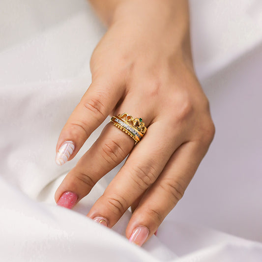 Mano de mujer con un anillo en forma de corona con el número 15 en oro amarillo de 18 quilates con cristales de color blanco y verde, hecho en Joyería Caracas. 