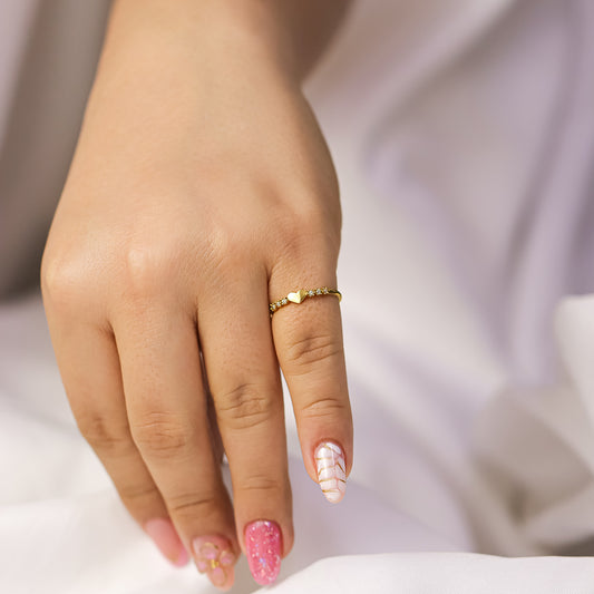 Mano de mujer con anillo en forma de corazón con 3 piedras en ambos laterales oro amarillo de 18k, hecho en Joyería Caracas.