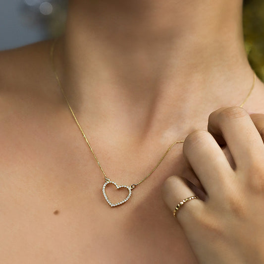 Cuello de mujer usando gargantilla con forma de corazón en oro amarillo de 18 quilates con cristales de color blanco, hecho en Joyería Caracas. 