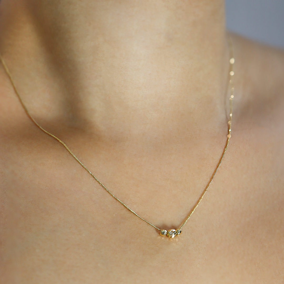 Cuello de mujer usando gargantilla mini cubana con esferas facetadas en oro amarillo de 18 quilates, hecho en Joyería Caracas. 