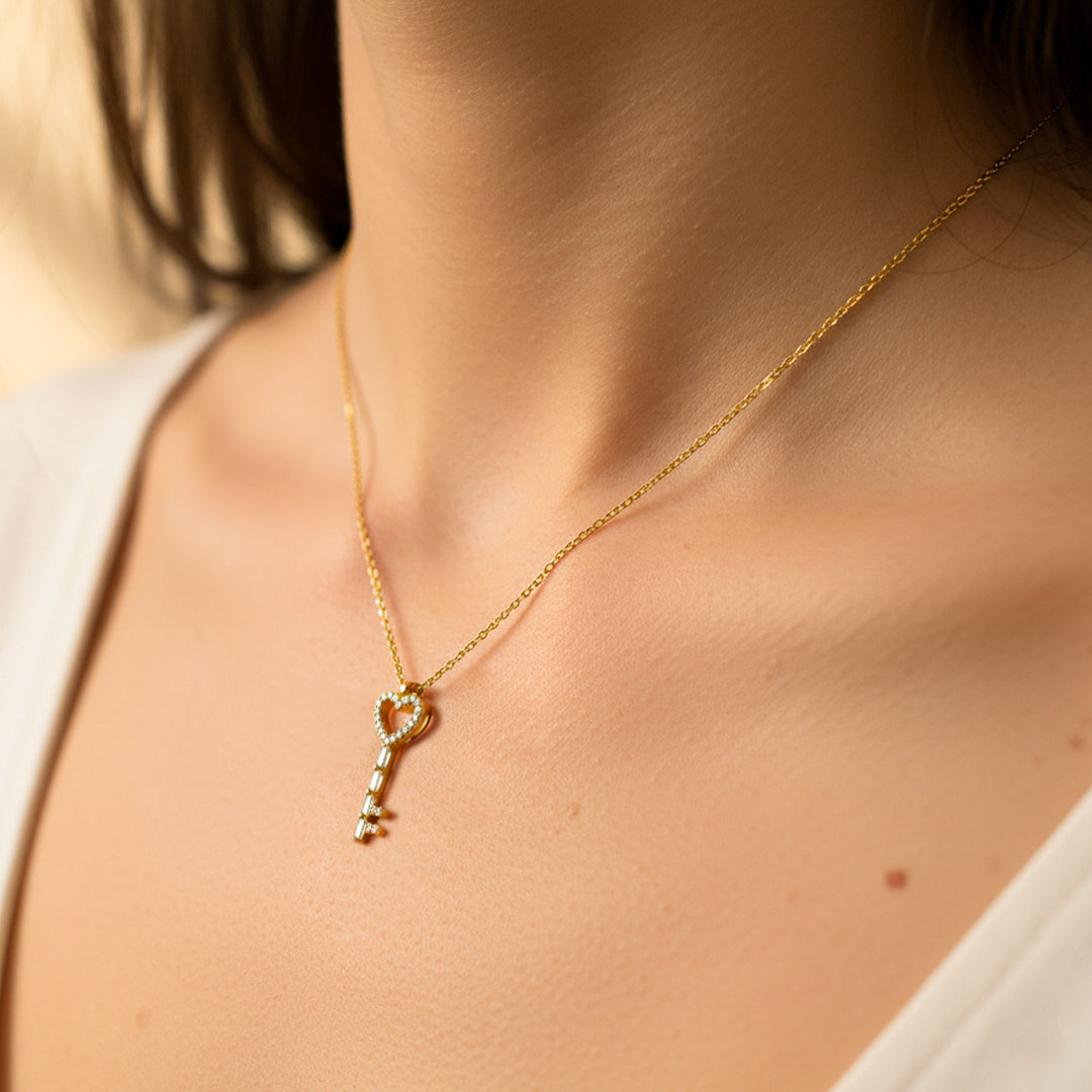 Cuello de mujer usando una gargantilla con dije en forma de llave en oro amarillo de 18 quilates con cristales de color blanco de Joyería Caracas. 