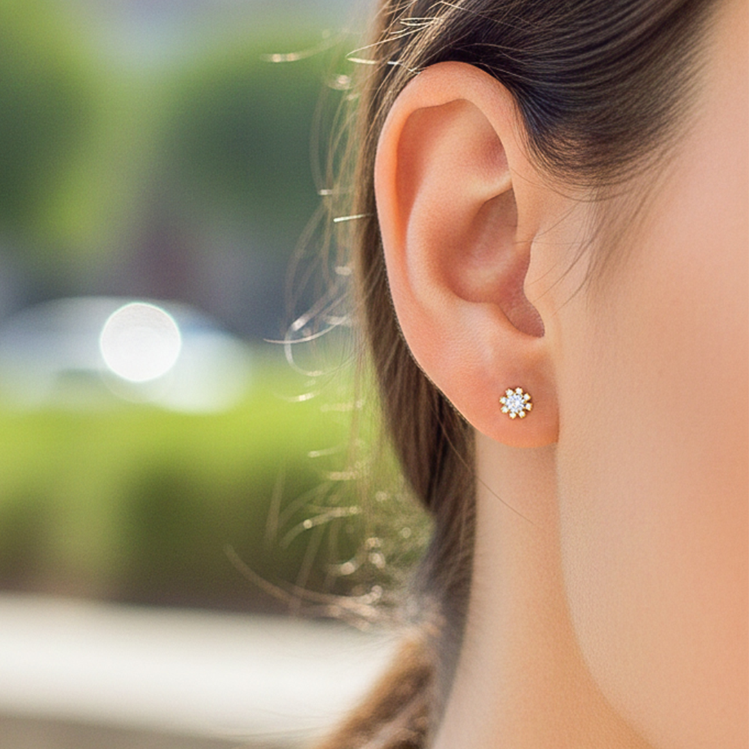 Oreja de modelo usando unos topitos en forma de flor en oro amarillo de 18 quilates con cristales de Joyería Caracas. 