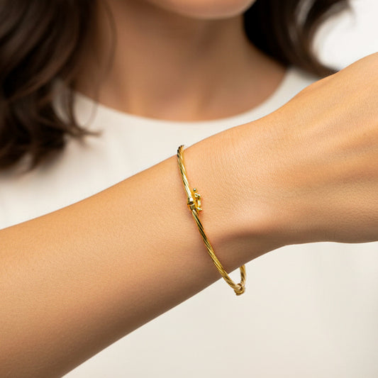 Mano de mujer usando una pulsera aro melcocha en oro amarillo de 18 quilates de Joyería Caracas.