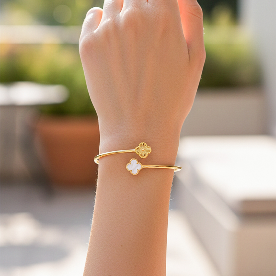 Mano de una modelo usando una pulsera aro con forma de tréboles en oro amarillo y con piedra nácar de Joyería Caracas.