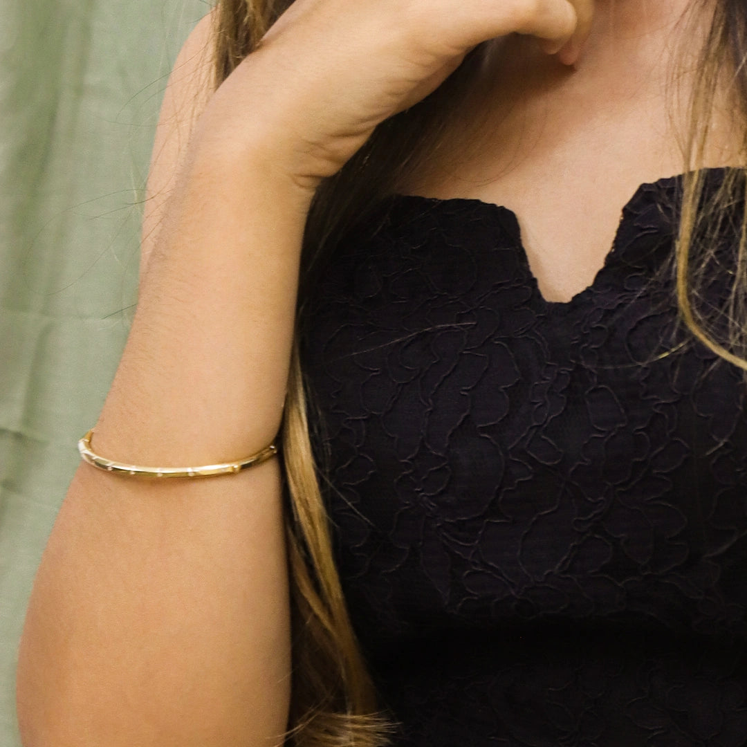 Brazo de mujer la cual usa una pulsera brazalete en oro amarillo de 18 quilates con cristales de color blanco de Joyería Caracas.