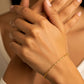 Mano de mujer usando una pulsera en tejido classic en oro amarillo de 18 quilates de Joyería Caracas. 