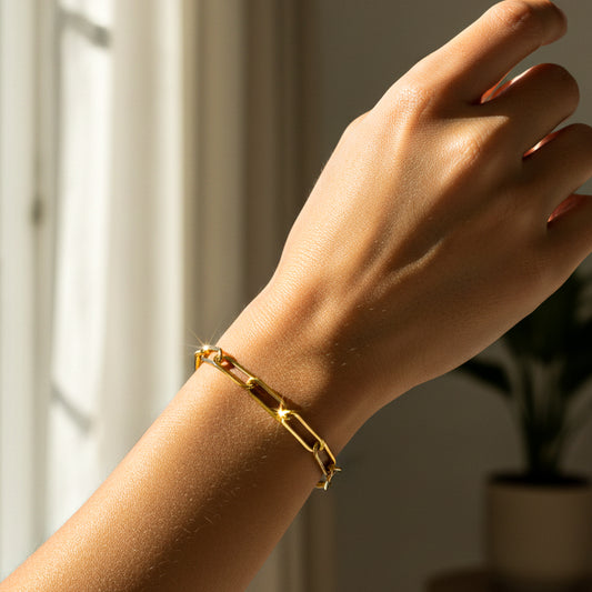 Mano de mujer usando una pulsera en tejido Clip XL en oro amarillo de 18 quilates de Joyería Caracas. 