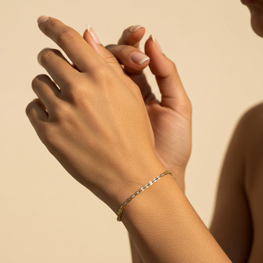 Mano de mujer usando una pulsera tejido escalera plana 3 oros de 18 quilates de Joyería Caracas. 