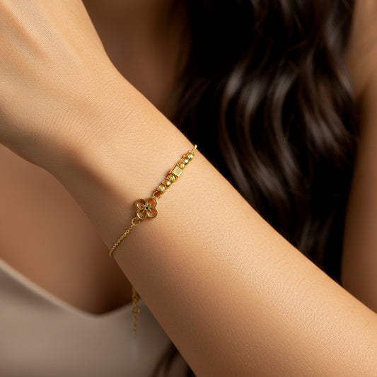 Mano de mujer usando una pulsera con forma de flor, esferas facetadas y un cuadrado en oro amarillo de 18 quilates de Joyería Caracas. 