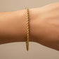 Mano de mujer usando una pulsera en tejido Lazo M en oro amarillo de 18 quilates de Joyería Caracas. 