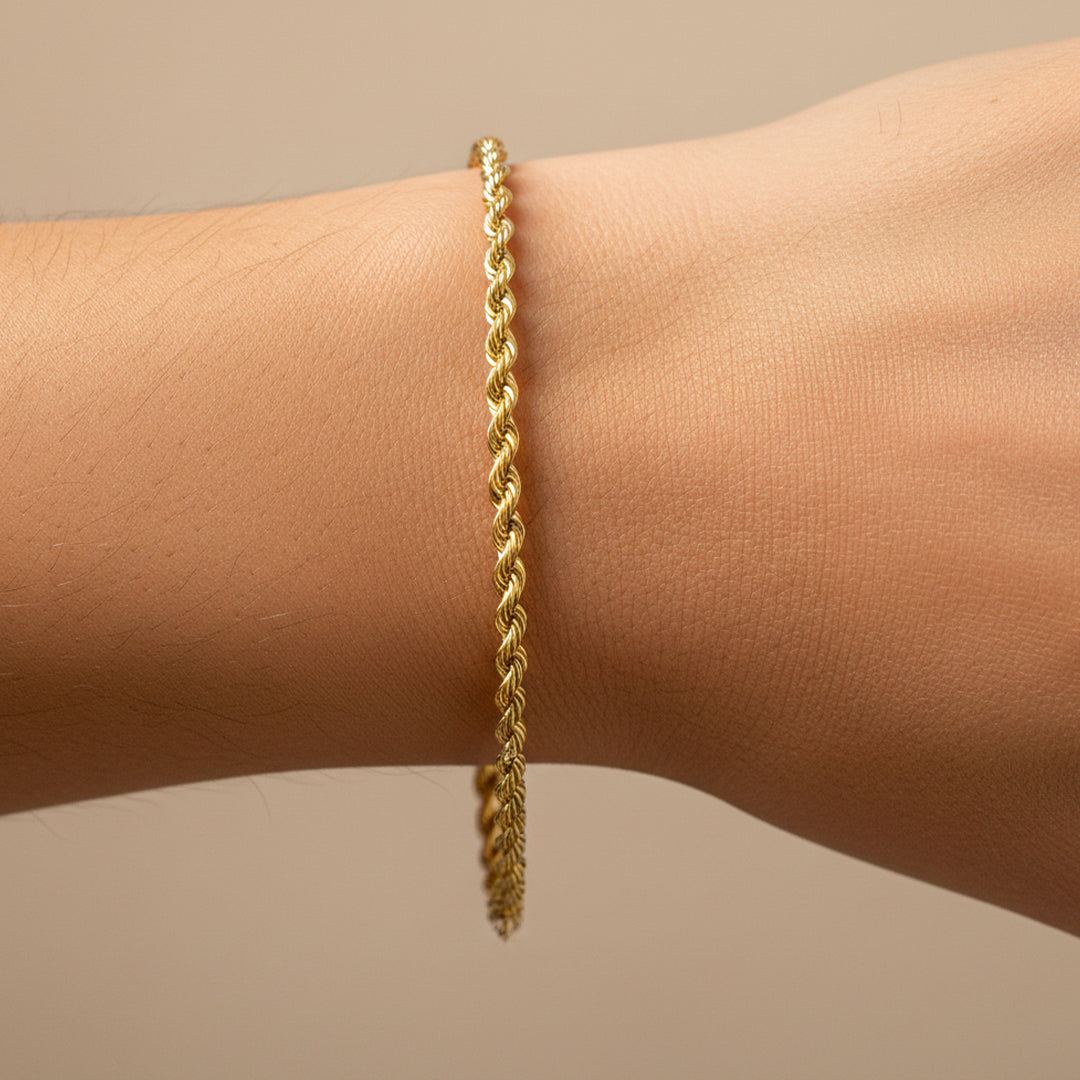 Mano de mujer usando una pulsera en tejido Lazo M en oro amarillo de 18 quilates de Joyería Caracas. 