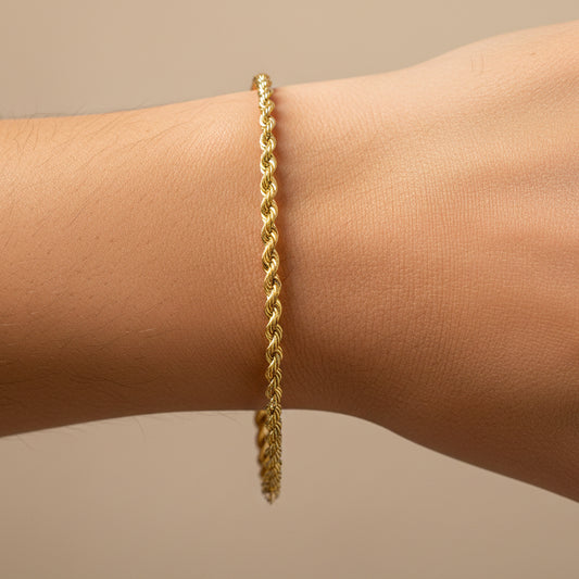 Mano de mujer usando una pulsera en tejido Lazo M en oro amarillo de 18 quilates de Joyería Caracas. 