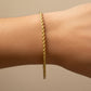 Mano de mujer usando una pulsera en tejido Lazo S en oro amarillo de 18 quilates de Joyería Caracas. 