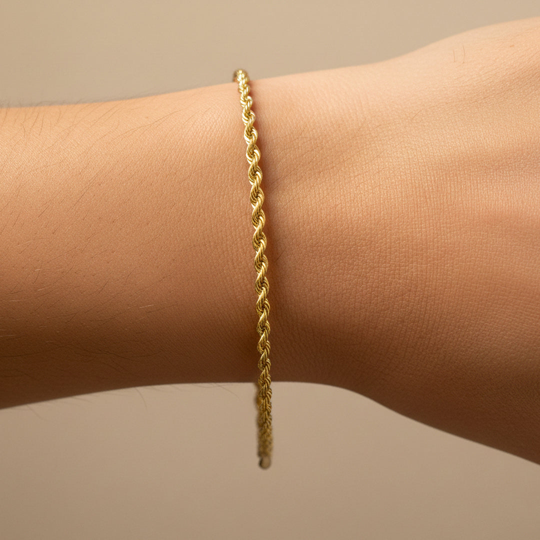 Mano de mujer usando una pulsera en tejido Lazo S en oro amarillo de 18 quilates de Joyería Caracas. 
