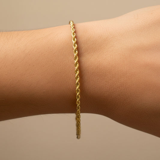 Mano de mujer usando una pulsera en tejido Lazo S en oro amarillo de 18 quilates de Joyería Caracas. 