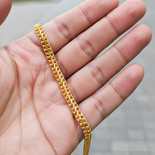Mano de una modelo usando una pulsera en tejido saduza en oro amarillo de Joyería Caracas.